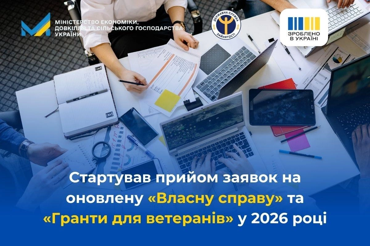 Люди за столом працюють з документами, ноутбуками та планшетами, обговорюючи державні програми
