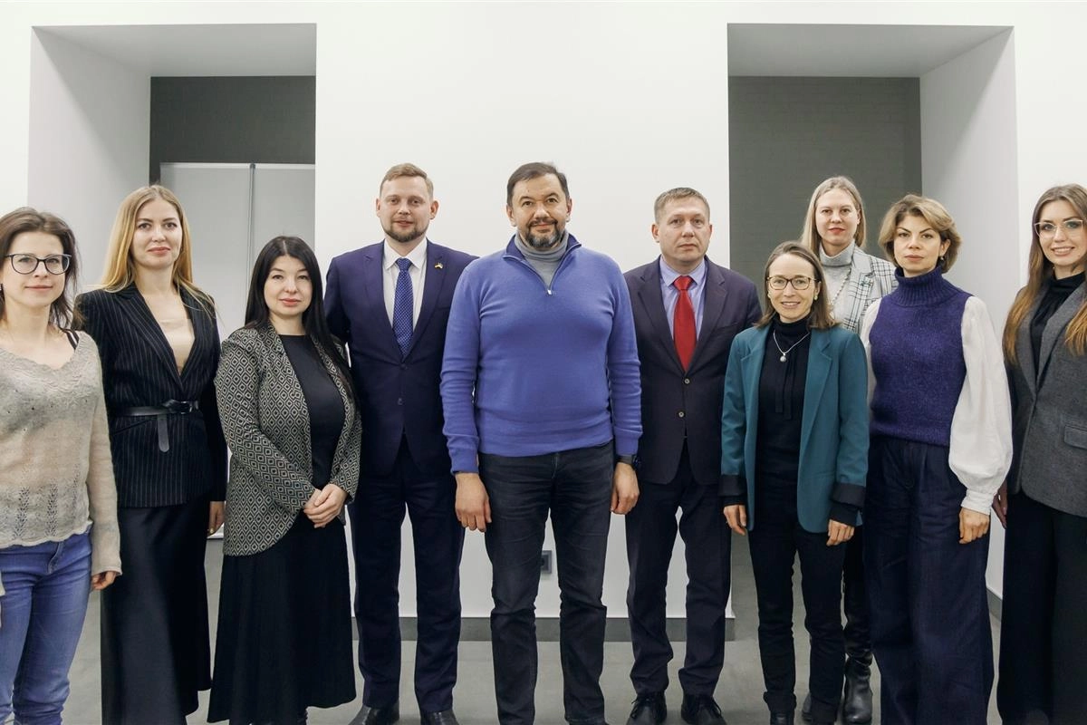 Група людей у діловому одязі стоїть разом у приміщенні на робочій зустрічі з питань кліматичної політики